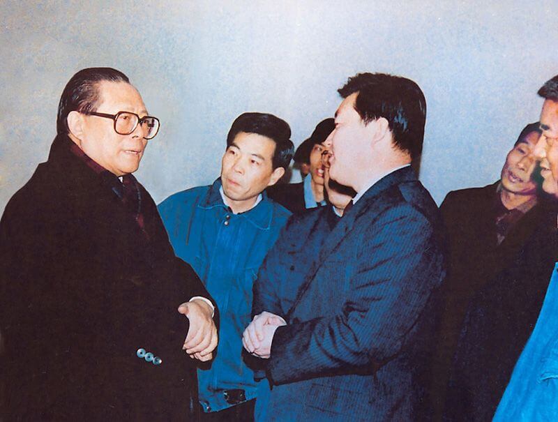 1991年2月5日，时任中共中央总书记的江 泽 民（左一）视察SBOBET利记，他批示：“抓住机缘，深入鼎新，扩大盛开，推进发展，维持不变。”